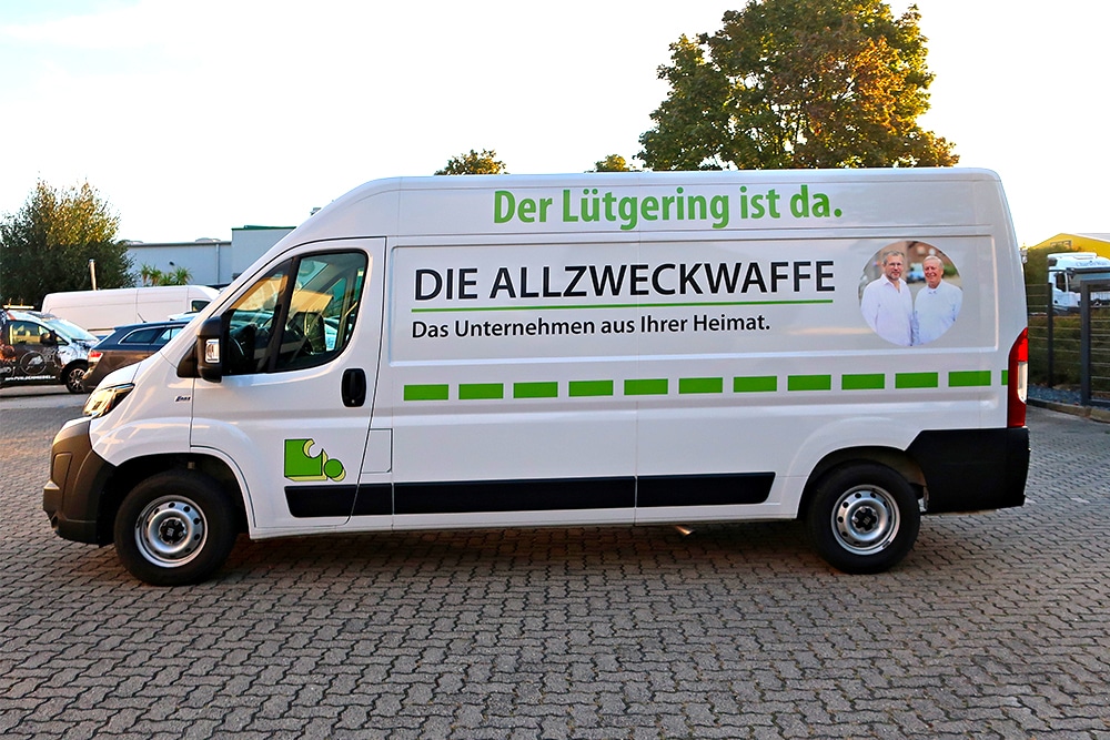 Ansicht der Fahrerseite eines fertig folierten Servicefahrzeugs auf einem Hof.