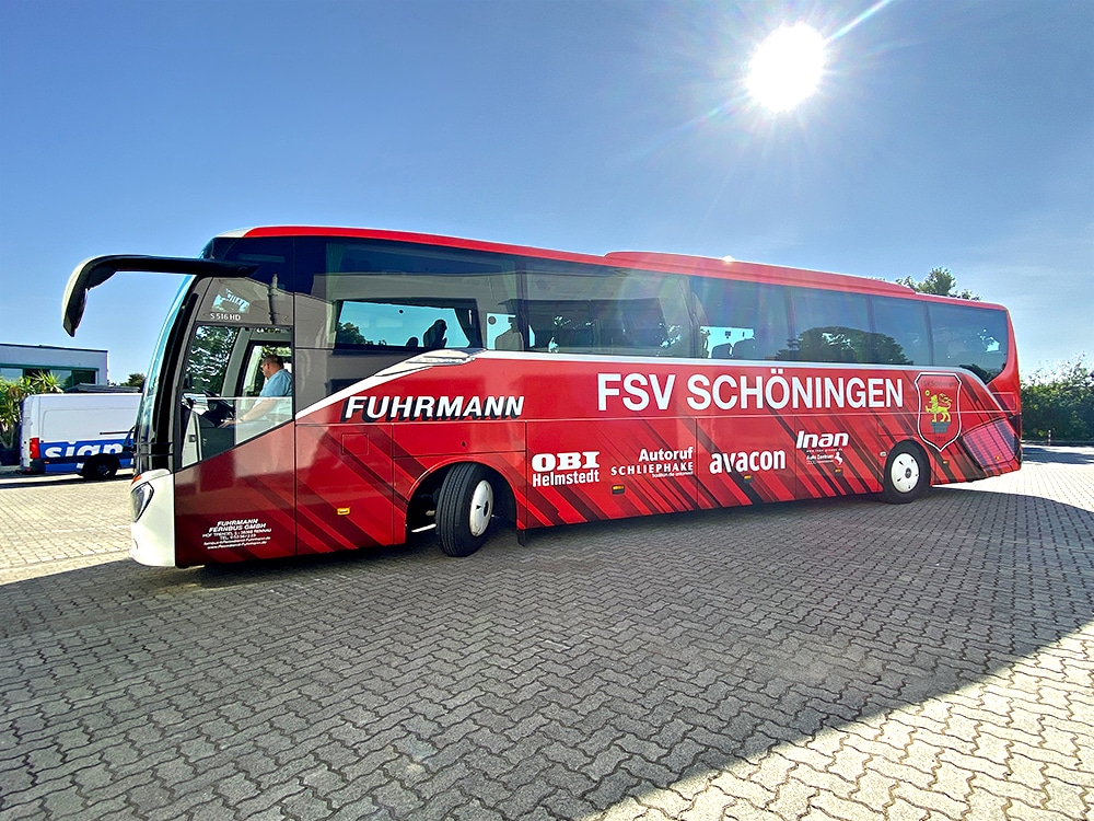 Seitenansicht des roten Reisebusses mit der markanten Beschriftung für den FSV Schöningen und Fuhrmann auf dem Betriebshof von P&K Schmiedel.